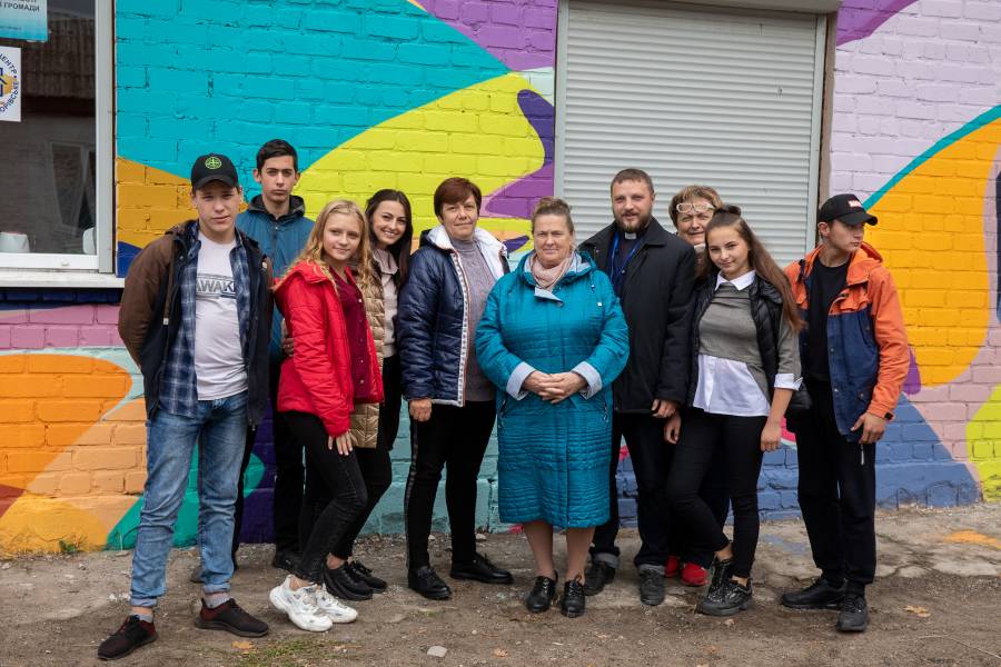 Jugendliche zusammen mit Olena Nebeska und Father Sergiy Palamarchyk von der Caritas Severodonetsk vor dem neuen Jugendzentrum in Borivske.