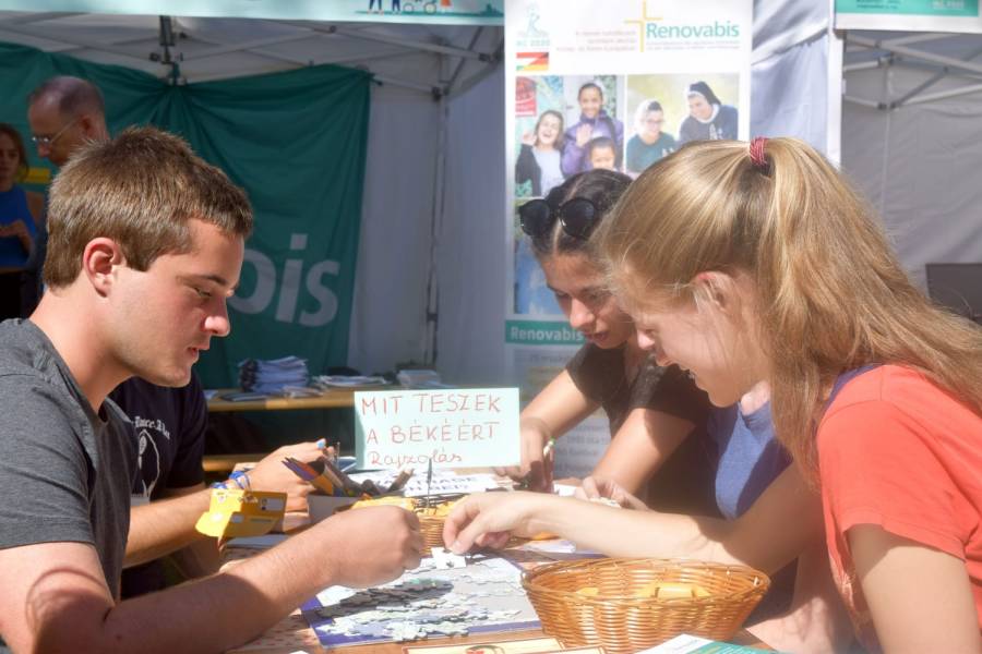 Jugendliche puzzeln am Infostand von Renovabis