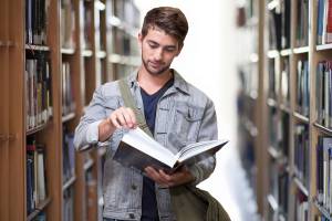 A young man reading in a library.