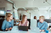 Drei junge Frauen mit Laptops in einem Büro.