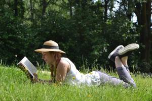 Ein Mädchen liest ein Buch auf einer Wiese