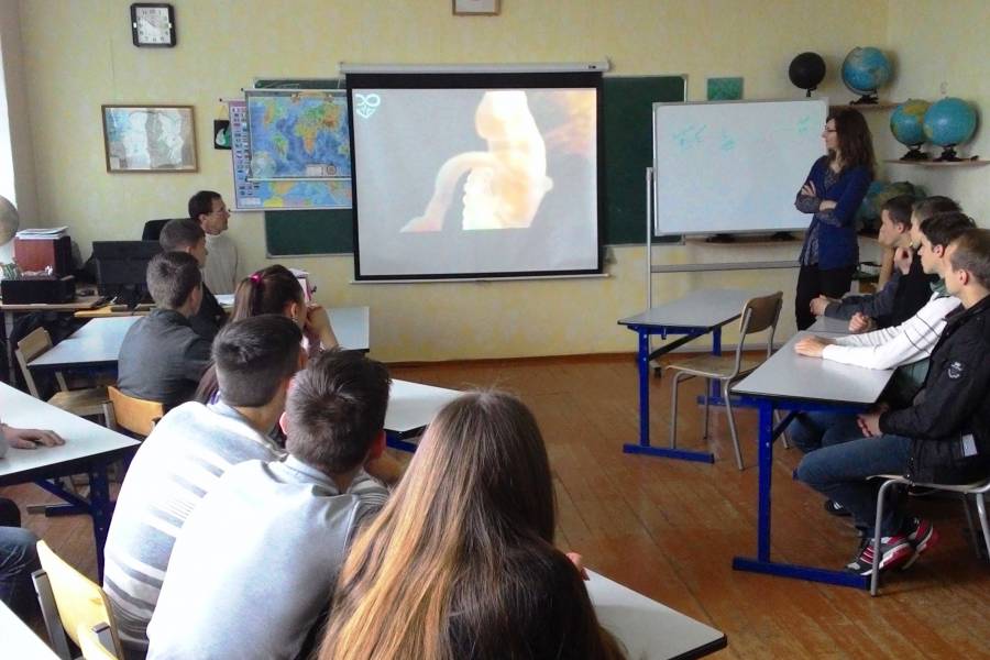 Schüler schauen im Klassenzimmer auf eine Leinwand.