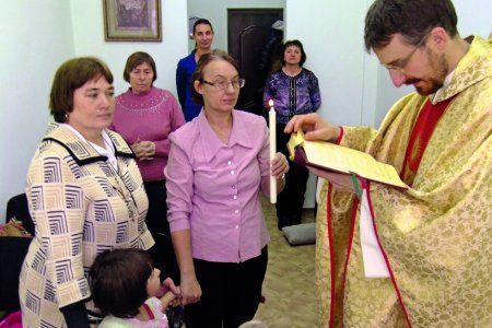 Priester und einige Gläubige feiern in einem kleinen Raum einen Gottesdienst