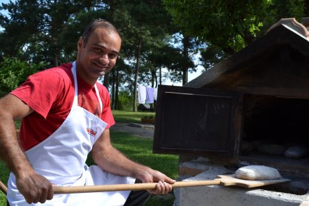 Mann schiebt ein Brot in den Ofen.