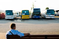 Parkende Busse, im Vordergrund sitzt ein Mann auf einer Bank.