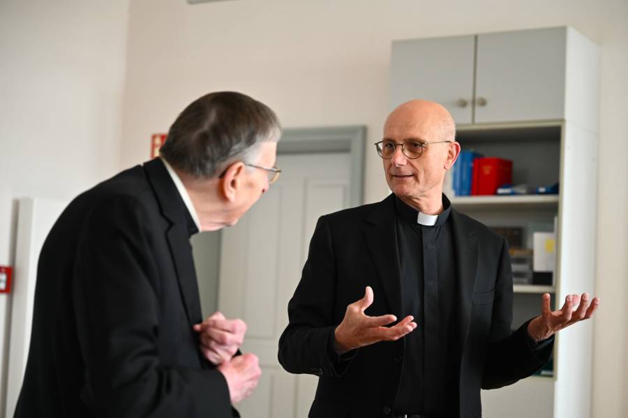 Rechts steht Prof. Thomas Schwartz und spricht. Links steht Kardinal Kurt Koch, der ihm aufmerksam zuhört.