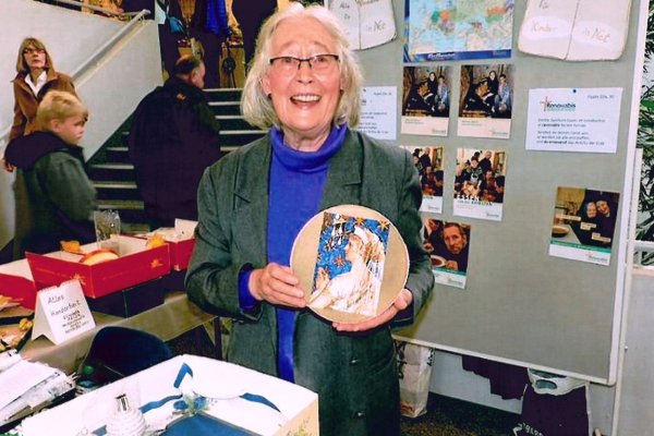 Elisabeth Heilen steht an ihrem Stand am Weihnachtsmarkt und hält eine Klosterarbeit in der Hand.