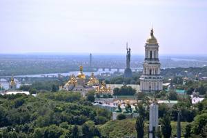 Das auf den Hügeln des Westufers des Dnepr gelegene Höhlenkloster und die Mutter-Heimat-Statue, dahinter der Dnepr und dessen flaches Ostufer (Kiew, Ukraine)